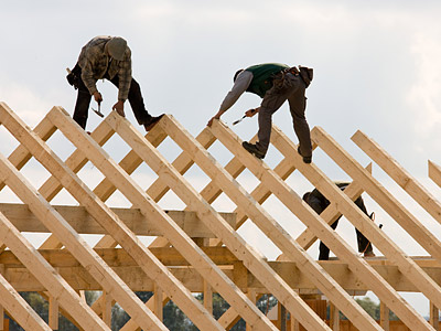Zwei Bauarbeiter arbeiten auf einem Holzgerüst.